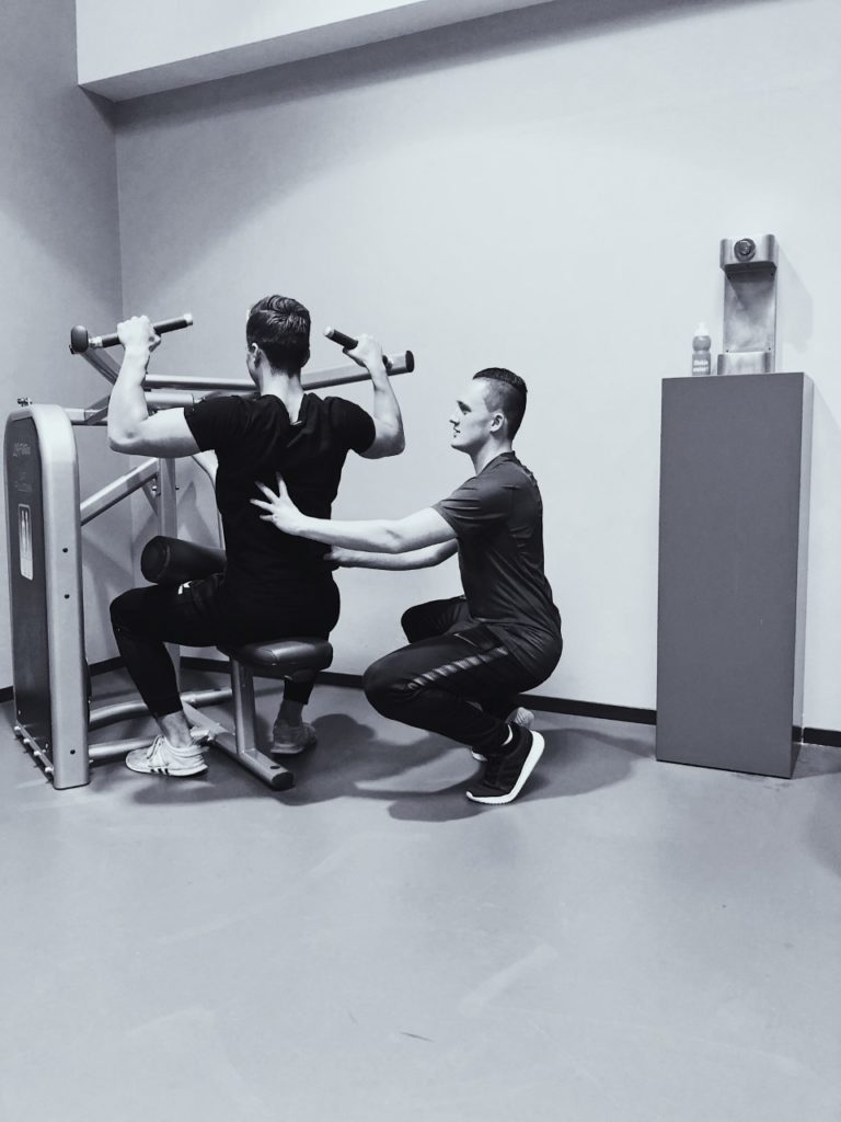 personal trainer ondersteund bij het uitvoeren van een oefening